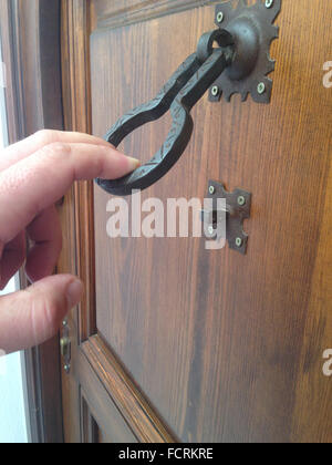 Man hand knocking with an old iron doorknocker. Selective focus Stock Photo