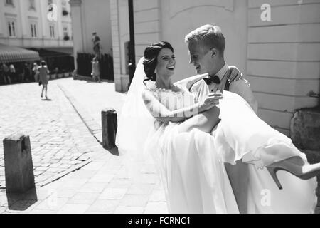 groom carries bride in his arms Stock Photo