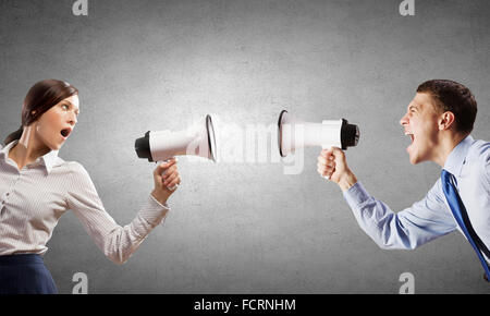Young furious people screaming agressively in megaphone Stock Photo