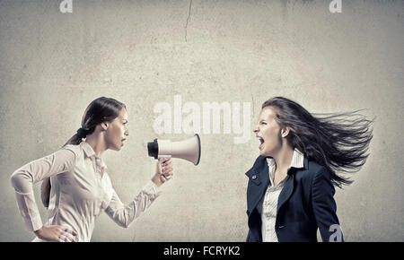 Young furious woman screaming agressively in megaphone Stock Photo