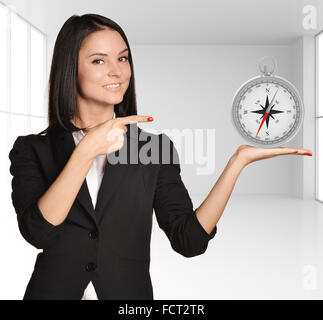 Office girl standing on background of light interior and holding compass Stock Photo