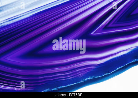 Detail view of a flat, polished and transparent slice of agate with arrow-shaped structures in blue against a white background Stock Photo