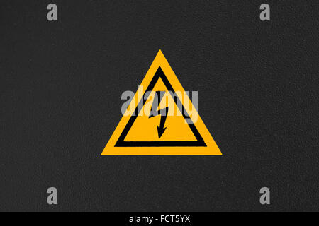 High voltage triangle warning sign mounted on black metal wall Stock Photo