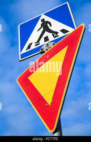 Pedestrian crossing and give way. Two road signs above blue sky background in Finland Stock Photo