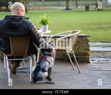 Man sat outside of cafe making a fuss of his dog. Stock Photo