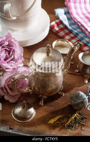 Tea Pot with dry Tea and Dishware on a wooden Table Stock Photo