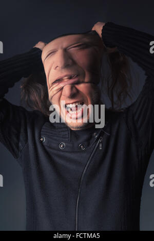 A man tears off the mask from his face Stock Photo