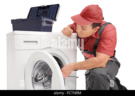 Studio shot of a young repairman fixing a washing machine isolated on white background Stock Photo