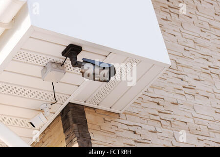 Infrared security day and night cameras on wall of house covered with lite brown decorative slate stone wall surface. Stock Photo