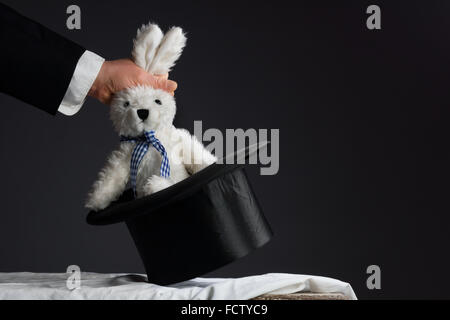 Man in suit pulling a rabbit out of the topper hat Stock Photo