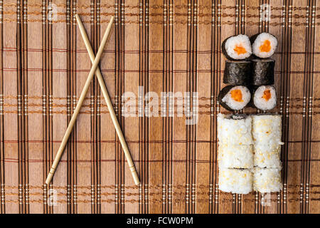 chopsticks and sushi roll on bamboo mat. background menu Stock Photo