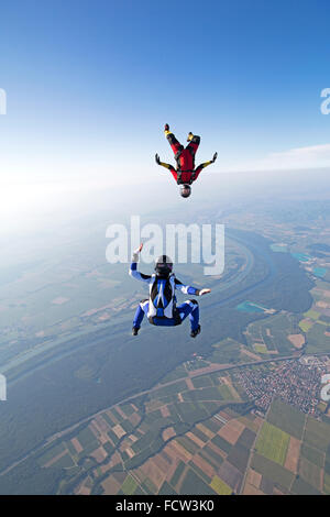 Two freefly skydivers are training the sit- & head-down formation. Thereby they fly with over 120 mph speed in the sky together. Stock Photo