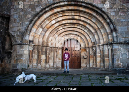 Cantabria, Spain. 24th Jan, 2016. A child looks like two dogs playing in the main entrance of the church of Santa Cruz in Castañeda (Cantabria) .monumento Romanesque twelfth century. Credit:  JOAQUIN GOMEZ SASTRE/Alamy Live News Stock Photo