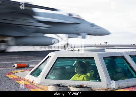 A US Navy air traffic controller launches pilot a F/A-18C Horne fighter aircraft from the bubble on the flight deck of the nuclear Nimitz-class aircraft carrier USS John C. Stennis January 22, 2016 in the Western Pacific. Stock Photo