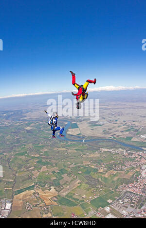 This skydive freefly team is training the sit-fly and head-down formation. With over 125 mph they fly together in the blue sky. Stock Photo