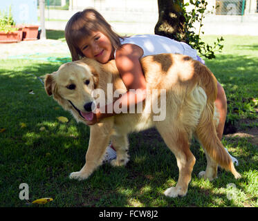 Cuddles and hugs between a sweet little girl and her dog Stock Photo