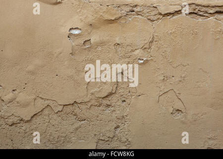 Old ochre painted stucco wall with cracked plaster. Background texture. Stock Photo