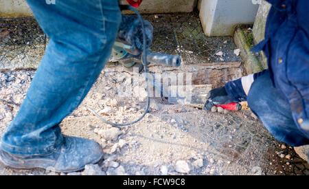 Construction site - workers using Jackhammer and trowel performing track on the floor sidewalk Selective focus and motion blur Stock Photo