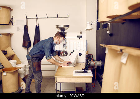 Man using a laptop in modern work space with machinery Stock Photo
