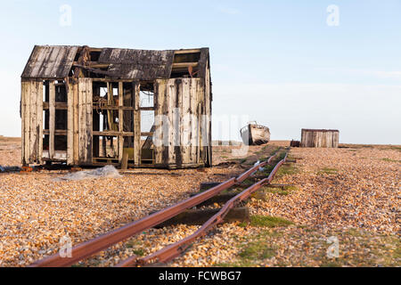 Abandoned fishing hut, transport tracks and old fishing boat on the shingle beach in Dungeness, Kent, England Stock Photo