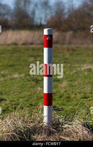Striped red and white signal poles barricade in front of greenfield Stock Photo