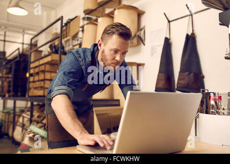 Serious young business owner using laptop in his workshop Stock Photo