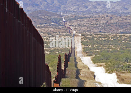 US border fence in Santa Cruz stretching into the distance leading to Nogales Sonora, Mexico and Santa Cruz County Arizona USA Stock Photo