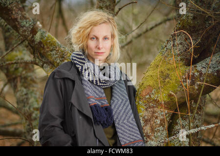 A female hiker standing by a tree in the countryside in rural Scotland Stock Photo