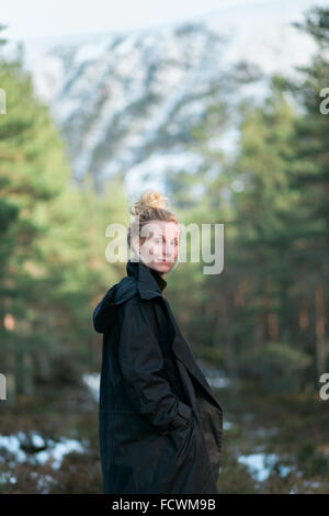 A woman hiker walking through a forest in rural Scotland Stock Photo