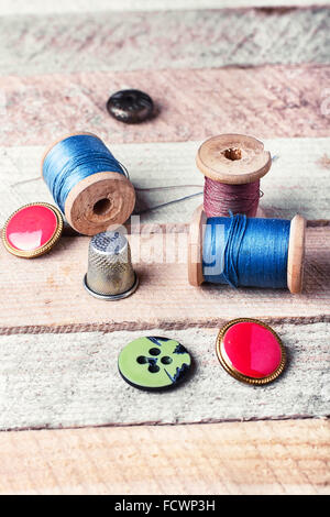 spools of thread and various buttons on wooden background Stock Photo