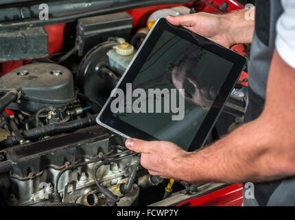 Mechanic using a tablet pc at the repair garage Stock Photo