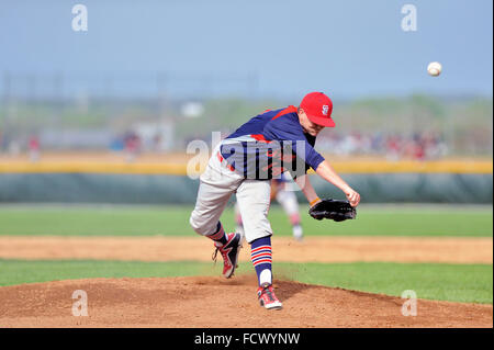 Pitcher delivering a pitch to a waiting hitter during a high school baseball game. USA. Stock Photo