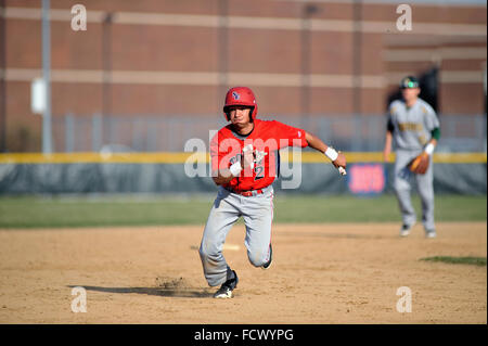 High school runner putting it into gear as he watches ground ball head into left field that allowed him to come around to score. USA. Stock Photo