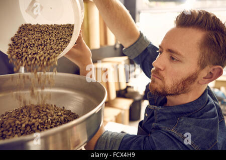 Man pouring coffee beans into a roasting machine Stock Photo