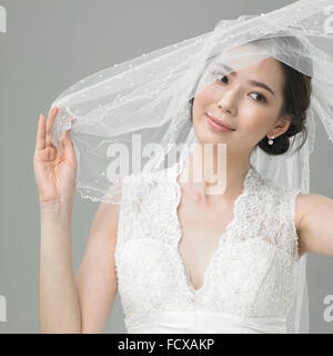 Bride in wedding dress lifting her veil and looking down Stock Photo