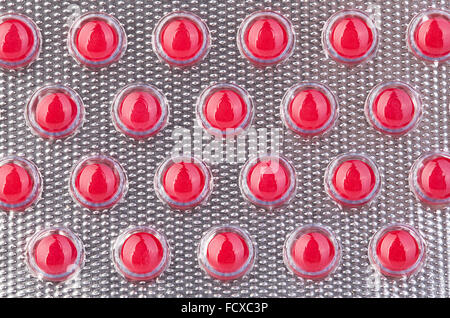 Red pills in blister close-up as a background. Stock Photo