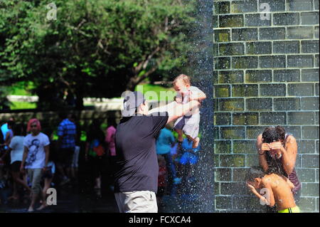 Father 'baptizes' daughter in Crown Foundation on a hot summer day in Millennium Park in Chicago, Illinois, USA. Stock Photo