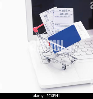 Credit card and receipts in a shopping cart with notebook computer