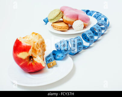 new diet concept, question sign in shape of measurment tape between red apple and donut isolated on white Stock Photo