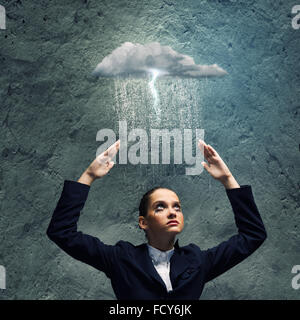 Young crying businesswoman with arms covering head from rain Stock Photo