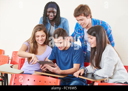 Happy interracial group of students with a tablet in class Stock Photo