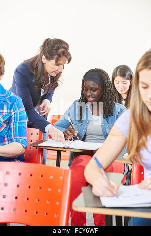 Teacher helping a student in class at school Stock Photo