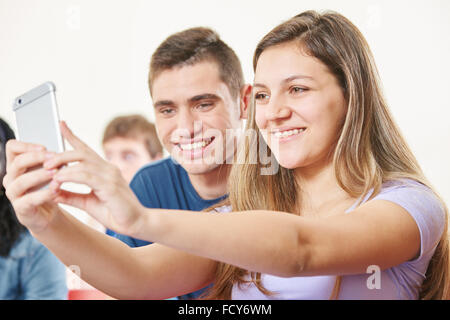 Two teenagers taking a selfie in class with their smartphone Stock Photo