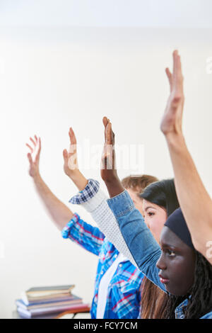 Pupils raising their hands in class and participate in class Stock Photo