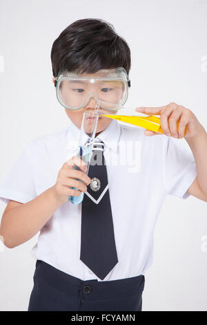 Elementary school boy in school uniforms and laboratory goggles doing a chemical experiment Stock Photo