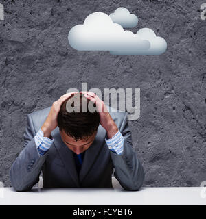 Depressed young businessman sitting wet under rain Stock Photo