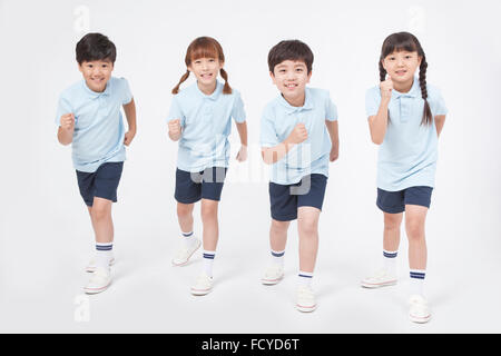 Four elementary school students in sportswear standing and gesturing running Stock Photo