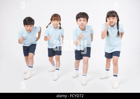 Four elementary school students in sportswear standing and being about to run Stock Photo