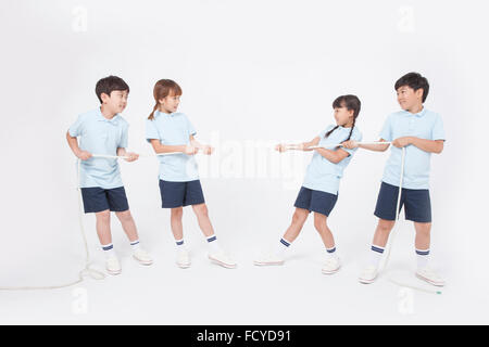 Four elementary school students in sportswear doing tug of war into two teams Stock Photo