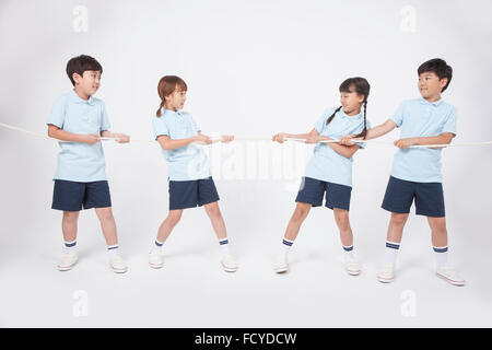 Four elementary school students in sportswear doing tug of war into two teams Stock Photo